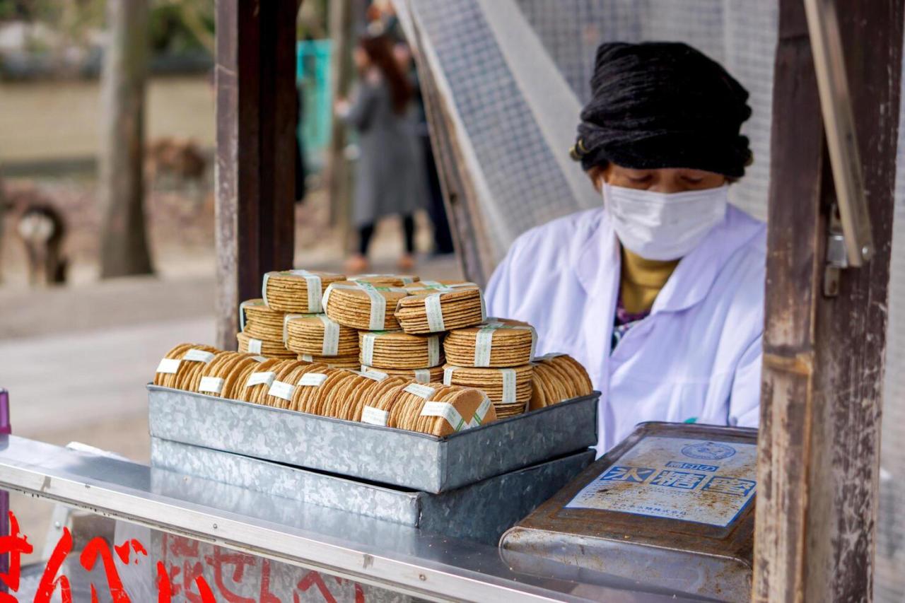 Nara City, Japan, 2023 - Japanese female trader and her Japanese snack Sembe for feed to deer in small booth, Sell at Nara natural park. 38601045 Stock Photo at Vecteezy